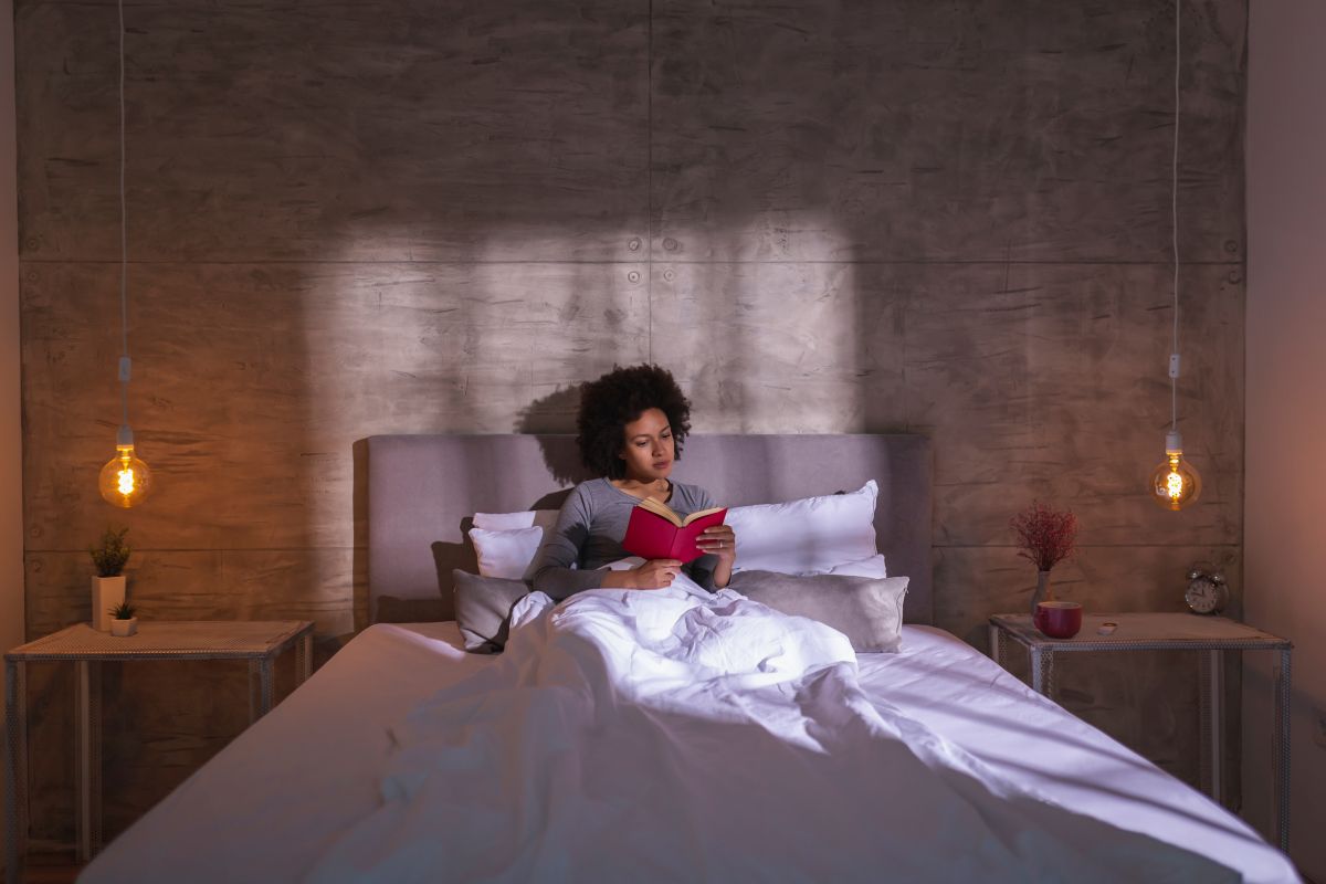 Woman reading a book in bed in the morning